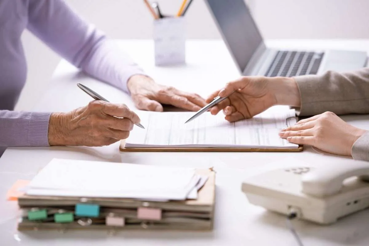An insurance agent discusses policy paperwork with a client