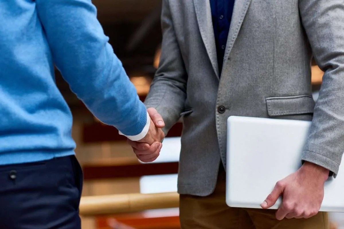 An insurance agent and client shake hands before a meeting