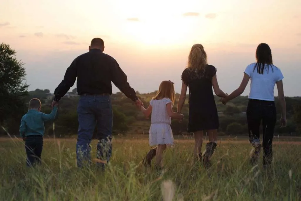 A family holds hands as they go for a walk at sunset