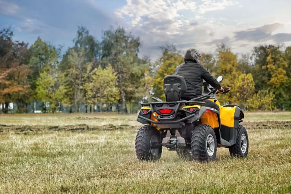 Person riding a yellow ATV off-road